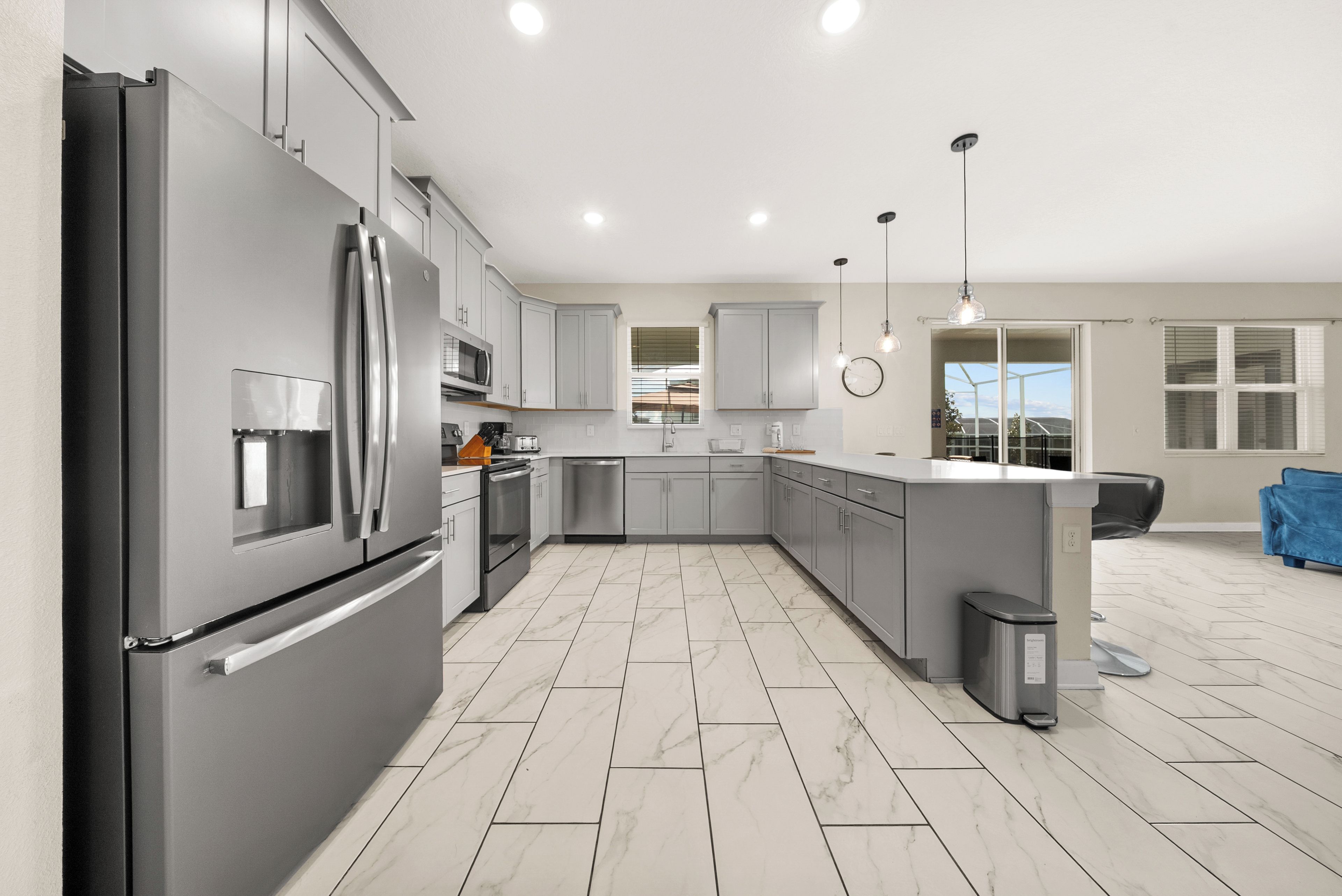 A modern kitchen with stainless steel appliances, grey cabinetry, and a herringbone floor pattern.
