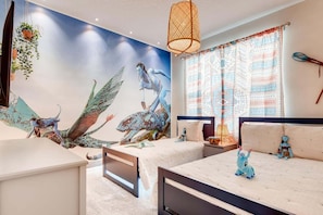 A bedroom with two beds, a mural, patterned curtains, and a hanging lamp.