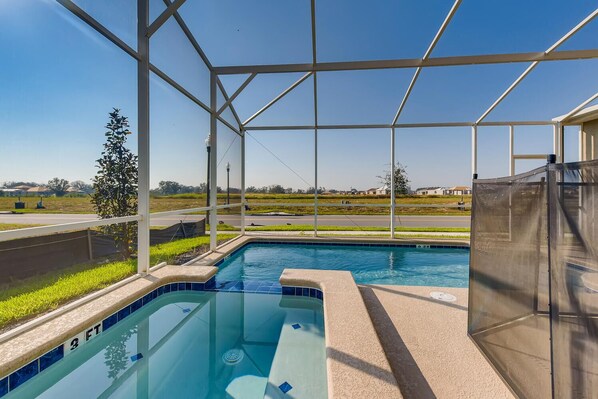 A swimming pool with a clear view of the surrounding landscape, enclosed by a white structure.