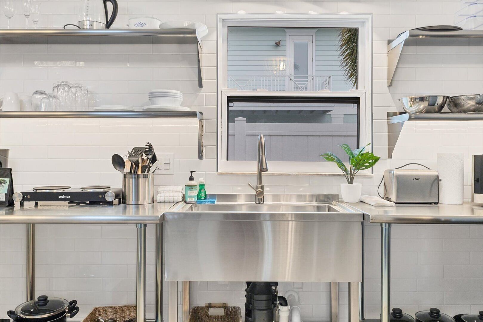 A modern kitchen with stainless steel appliances, a built-in oven, and a window overlooking a balcony.