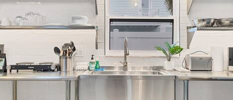 A modern kitchen with stainless steel appliances, a built-in oven, and a window overlooking a balcony.