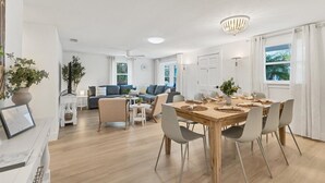 A spacious living area with a dining table set for four, a sofa set, and a chandelier. - Magnolia walk to beach/shops, Ami perfect Location (Anna Maria)