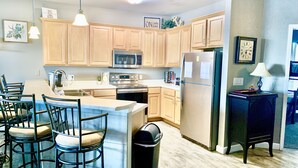 Una cocina moderna con armarios de madera, electrodomésticos de acero inoxidable y una isla central con taburetes de bar.