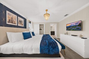 A hotel room with a bed, a desk, a television, and artwork on the walls.