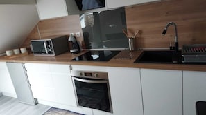 Una cocina moderna con horno empotrado, microondas y lavabo.