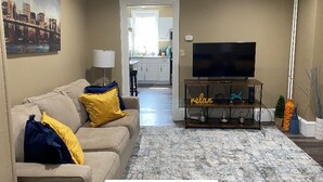 Ein Wohnzimmer mit einer Couch, einem Fernseher und einem Teppich.