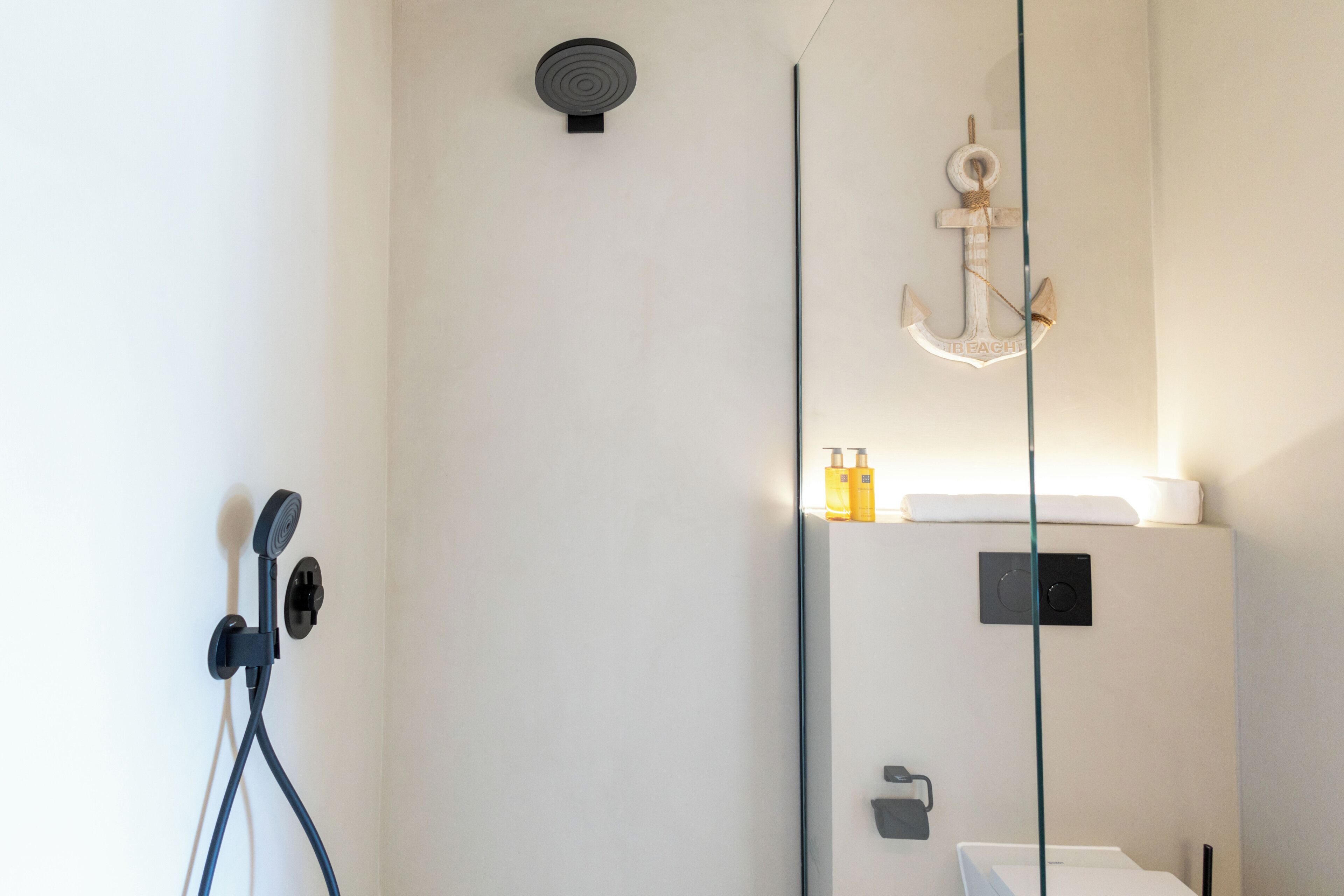Un baño moderno con ducha, espejo y lámpara mural.