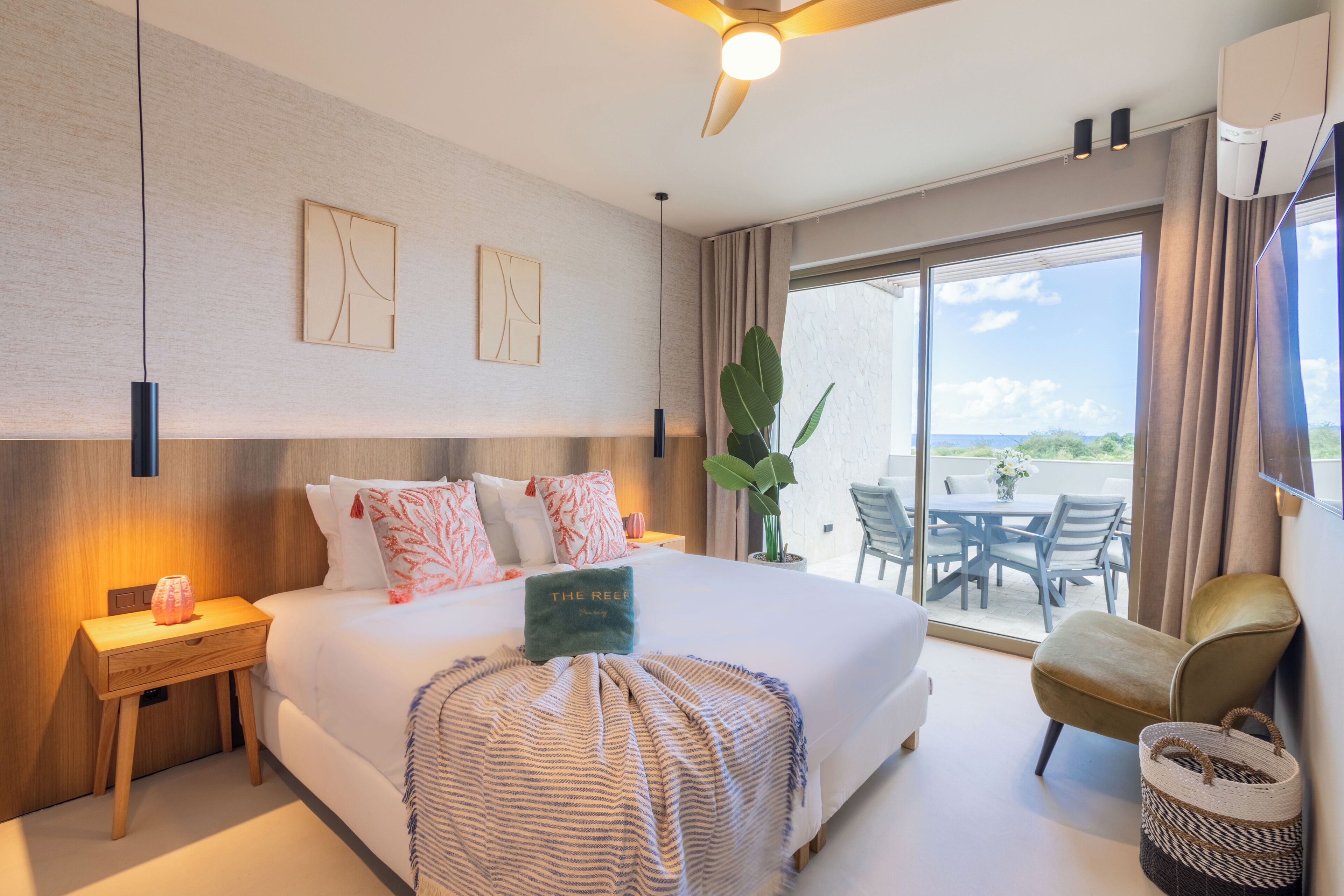 Habitación de hotel con cama, mesita de noche, una silla, un ventanal grande y un balcón.