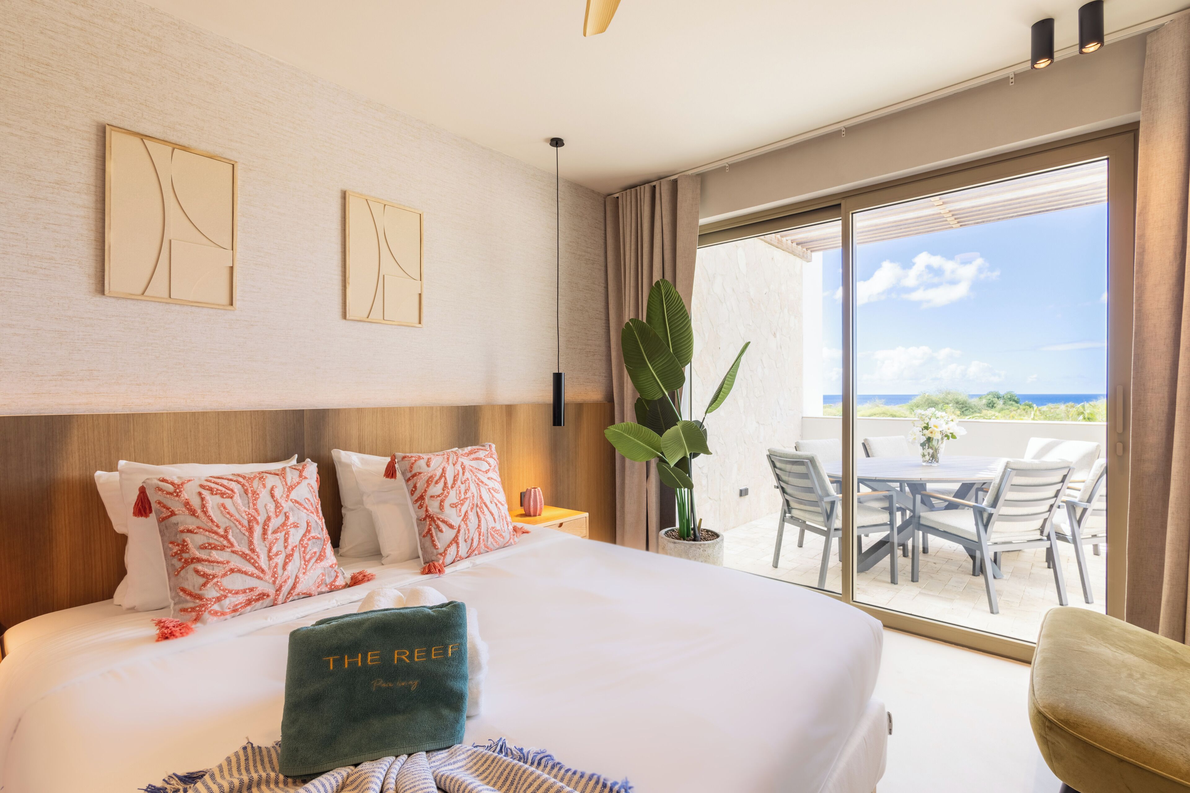 A hotel room with a large bed, a view of the outdoors, and a balcony with a table and chairs.