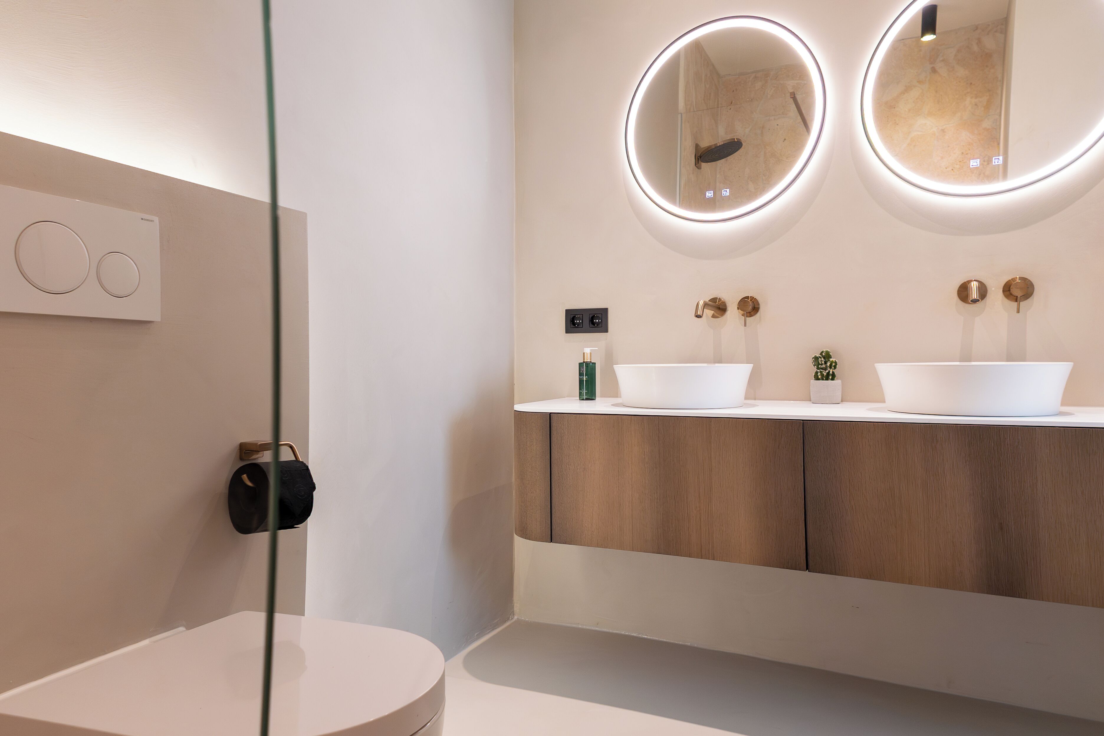 A modern bathroom with two sinks, wooden cabinets, and a glass shower enclosure.
