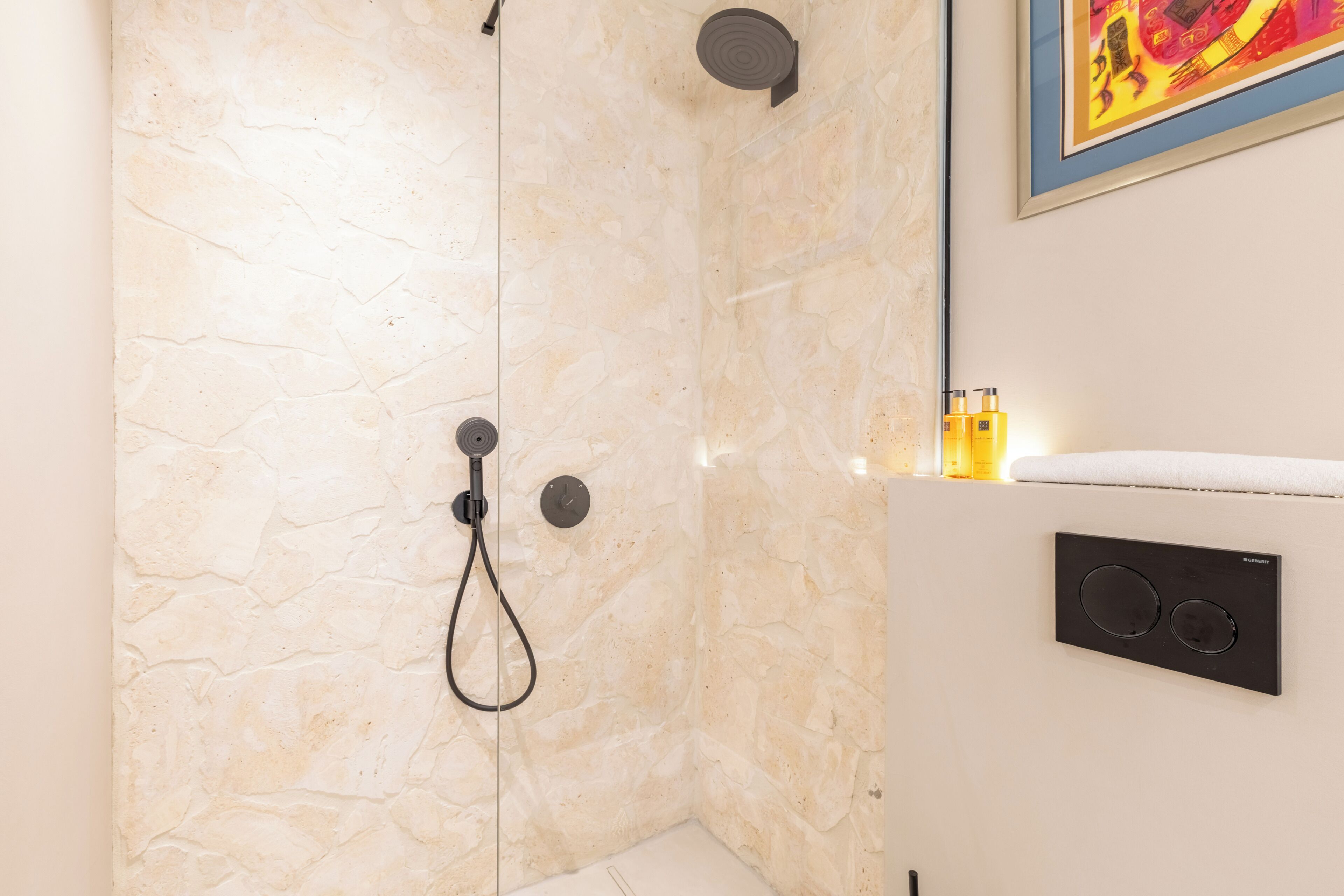 A bathroom with a stone wall, a showerhead, and a built-in heater.