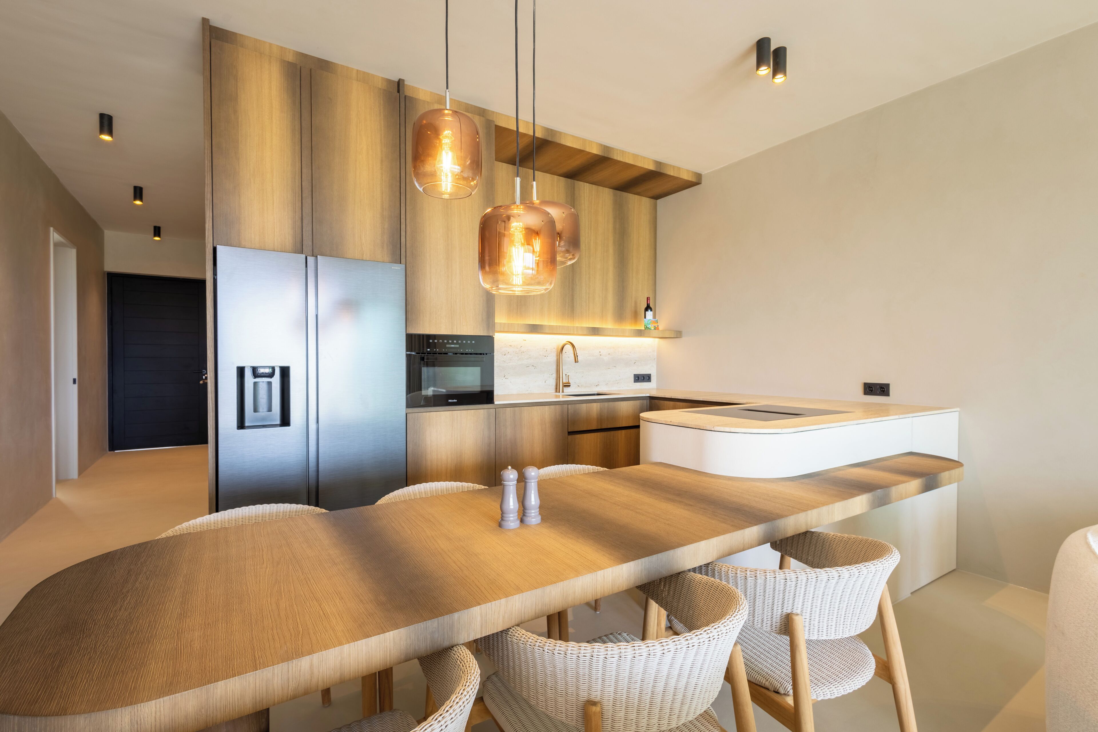 A modern kitchen with a central island, stainless steel appliances, and pendant lighting.