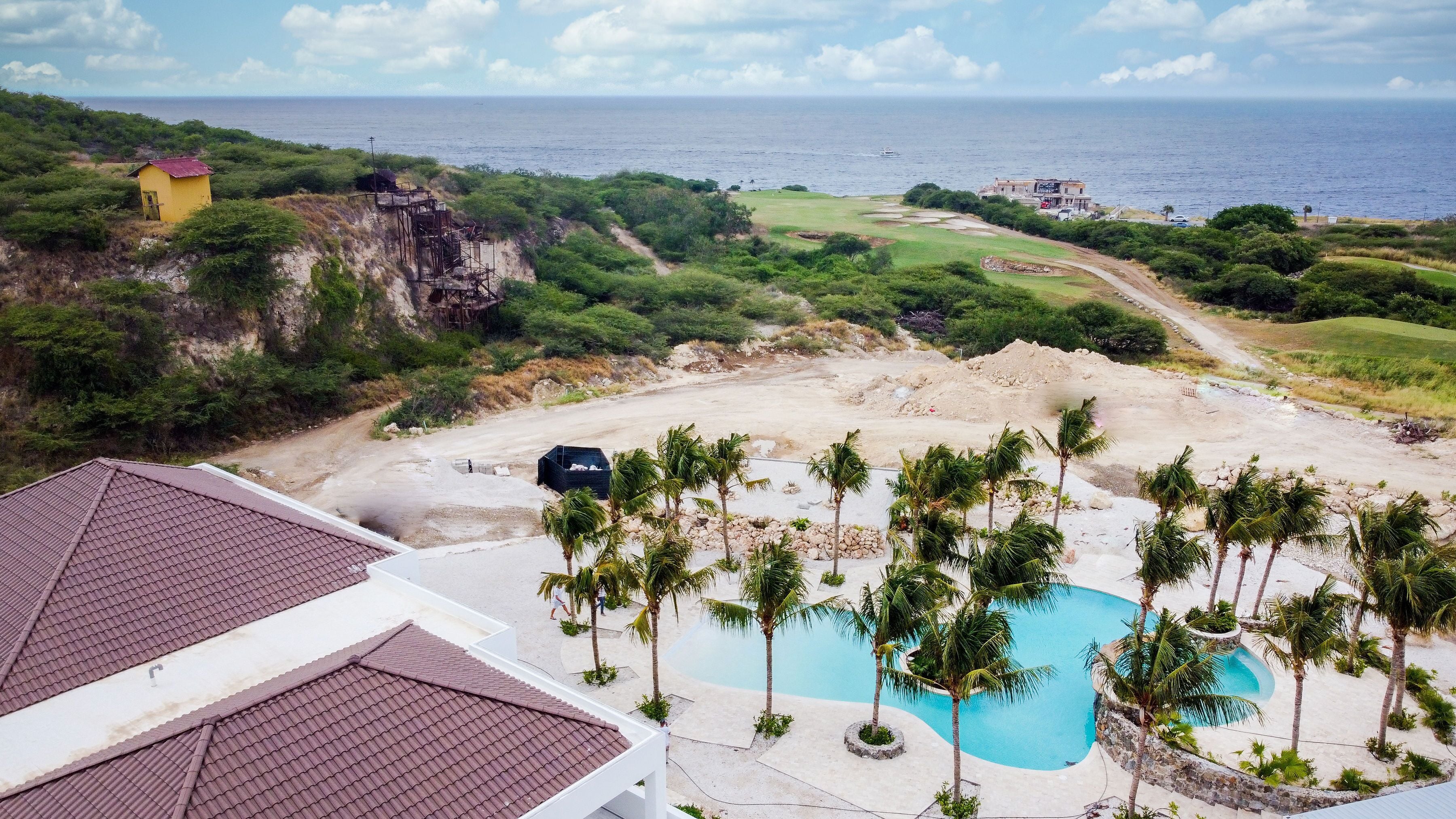 Een resort met een zwembad, palmbomen en uitzicht op de oceaan.