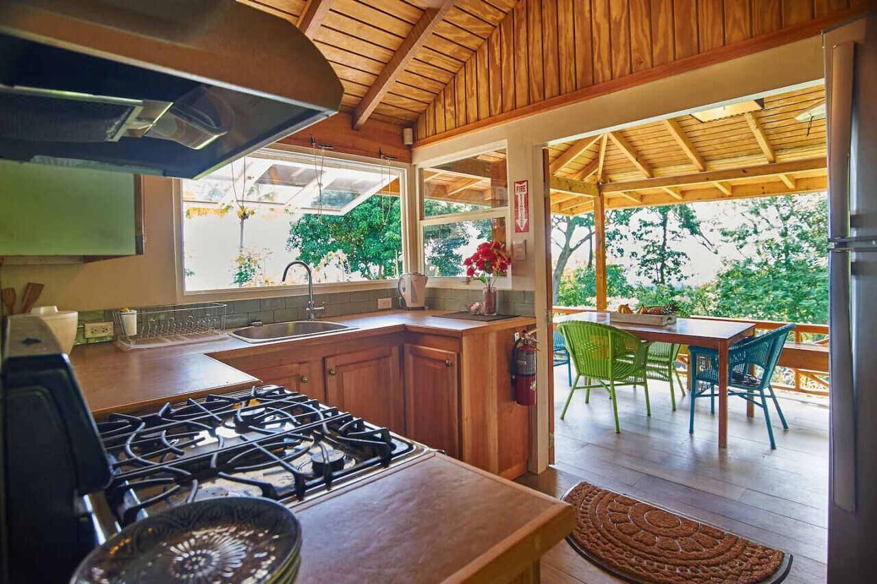 A kitchen with wooden cabinets, a gas stove, and a dining area with chairs and a table.