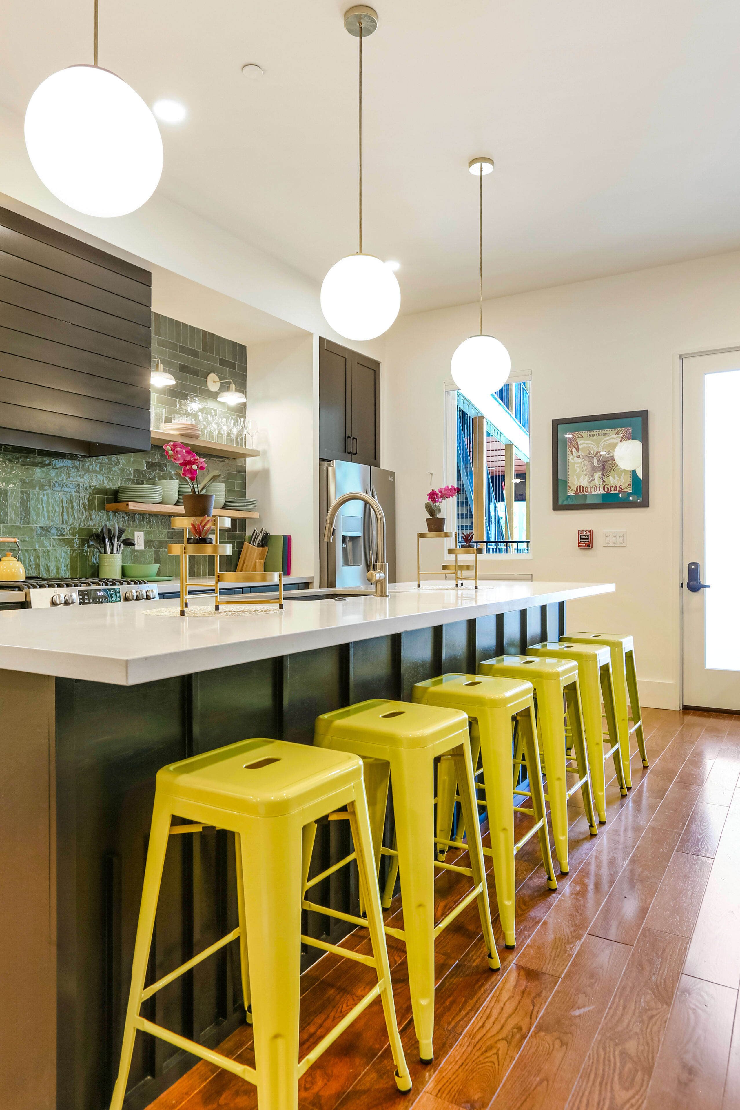 A modern kitchen with a central island, bar stools, and pendant lighting.