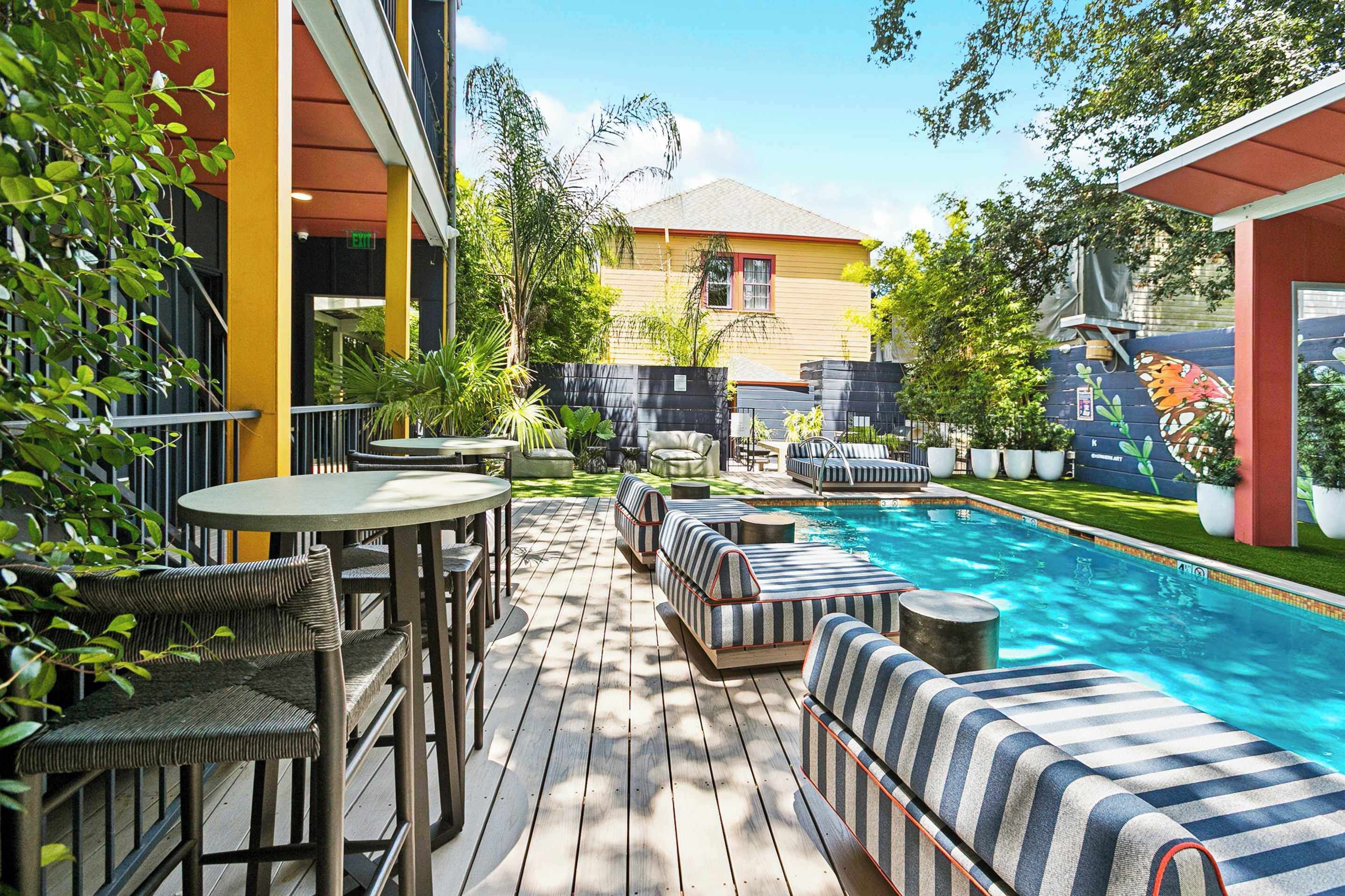 A poolside area with a wooden deck, lounge chairs, and a small table.