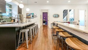 Een moderne keuken met een centraal eiland, barstoelen en hanglampen.