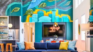 Una sala de estar moderna con un mural grande, un conjunto de sofá, una mesa de centro y una alfombra estampada.