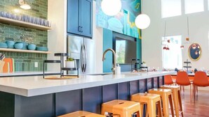 Una cocina moderna con una isla grande, taburetes de bar y un mural en la pared.