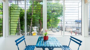 A room with a table and two chairs, a window with metal bars, and a view of the street outside. - Bamboo House (Santo Domingo)