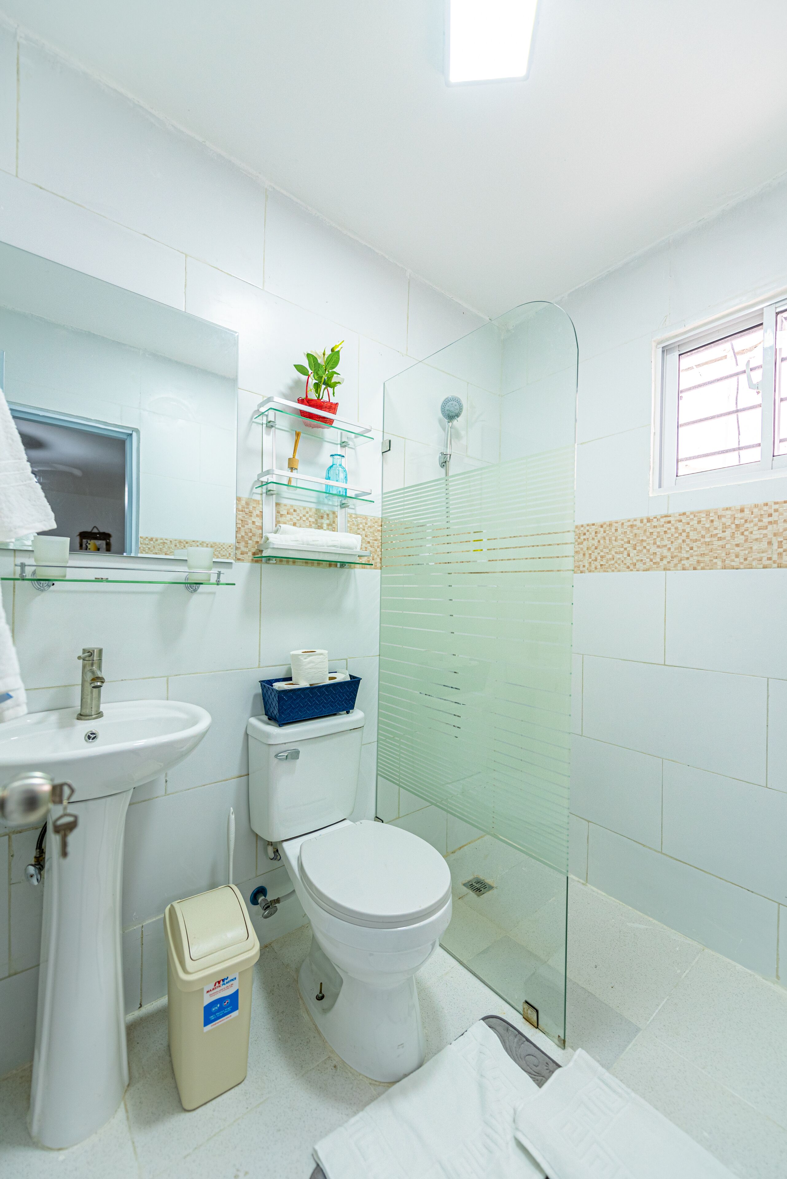 Un baño con cabina de ducha de vidrio, un lavabo, un inodoro y un espejo.