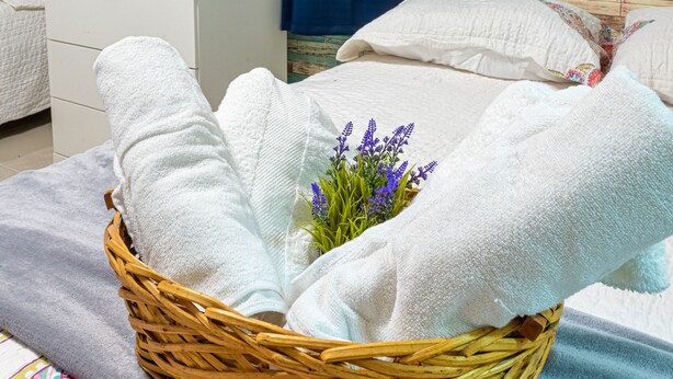 A neatly made bed with white linens and a basket of towels. - Bamboo House (Santo Domingo)