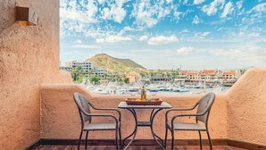 A balcony with wicker chairs and a table, overlooking a marina with boats and buildings. - Newly Remodeled Condo In The Cabo Marina (Cabo San Lucas)