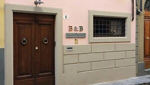 La façana d'un edifici amb portes de fusta dobles, una finestra amb reixes metàl·liques i un rètol que diu "B&B Le Stanze di Santa Teresa di Rieti".