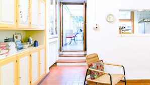 Un passadís estret amb una cadira i un taulell, que condueix a una zona exterior amb una cadira i un taulell.