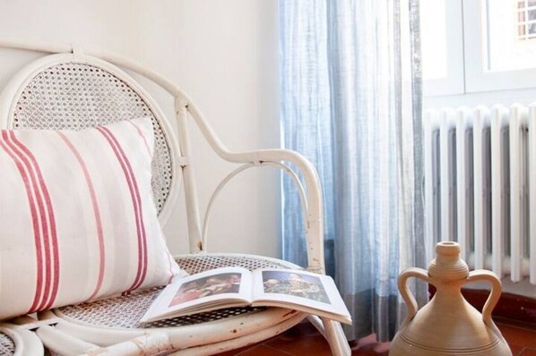 A white wicker chair with a striped pillow and an open book. - House in the Center of Florence! (Firenze)
