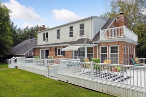 Una casa de dos pisos con un porche cubierto y un deck cercado.