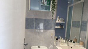 Een moderne badkamer met toilet, wastafel en spiegel.
