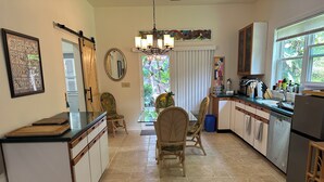 Una cocina con comedor, que cuenta con una araña, armarios de madera y vistas al exterior.