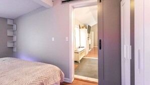 A bedroom with a bed, a wardrobe, and a door leading to a bathroom. - The Lilly Pad • Charming 1BR • Walk to Sylvan Beach (Sylvan Beach)