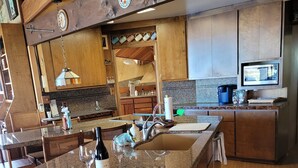 A kitchen with a granite countertop, wooden cabinets, and a built-in microwave. - Picturesque sunset views  perfect for couples, families and fishermen (Lakeport)