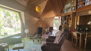 A cozy living room with a large window, a wooden ceiling, a sofa, a coffee table, and a bookshelf. - Picturesque sunset views  perfect for couples, families and fishermen (Lakeport)