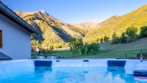 Ein Whirlpool mit Blick auf die Berge, ein weißes Gebäude und eine Rasenfläche.