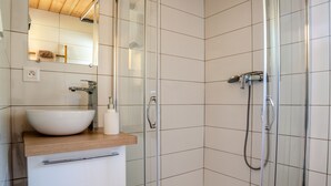 Ein modernes Badezimmer mit Waschbecken, Spiegel und Dusche.