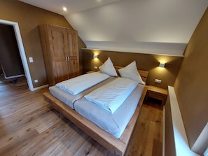 A bedroom with a wooden bed frame, two bedside tables, and a wardrobe.