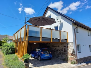 A two-story house with a car parked in the driveway and a satellite dish on the roof.