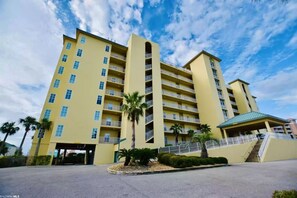 A multi-story hotel with balconies, a covered entrance, and palm trees.
