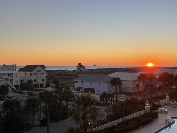 A coastal residential area with houses, a swimming pool, and a sunset view.