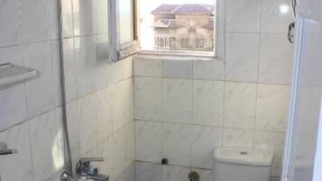 Une petite salle de bain avec des toilettes, un lavabo et une douche.