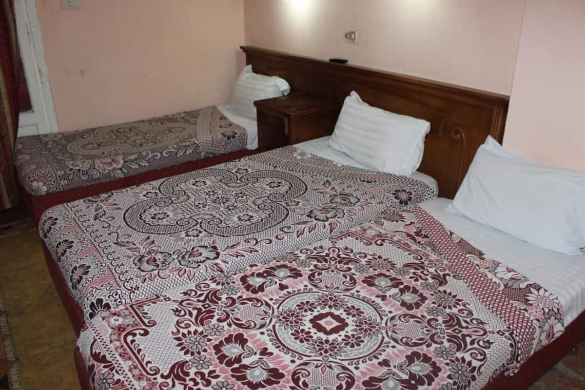 Ein Zimmer mit zwei Betten, jeweils mit einem gemusterten Bettüberwurf und weißen Kissen.