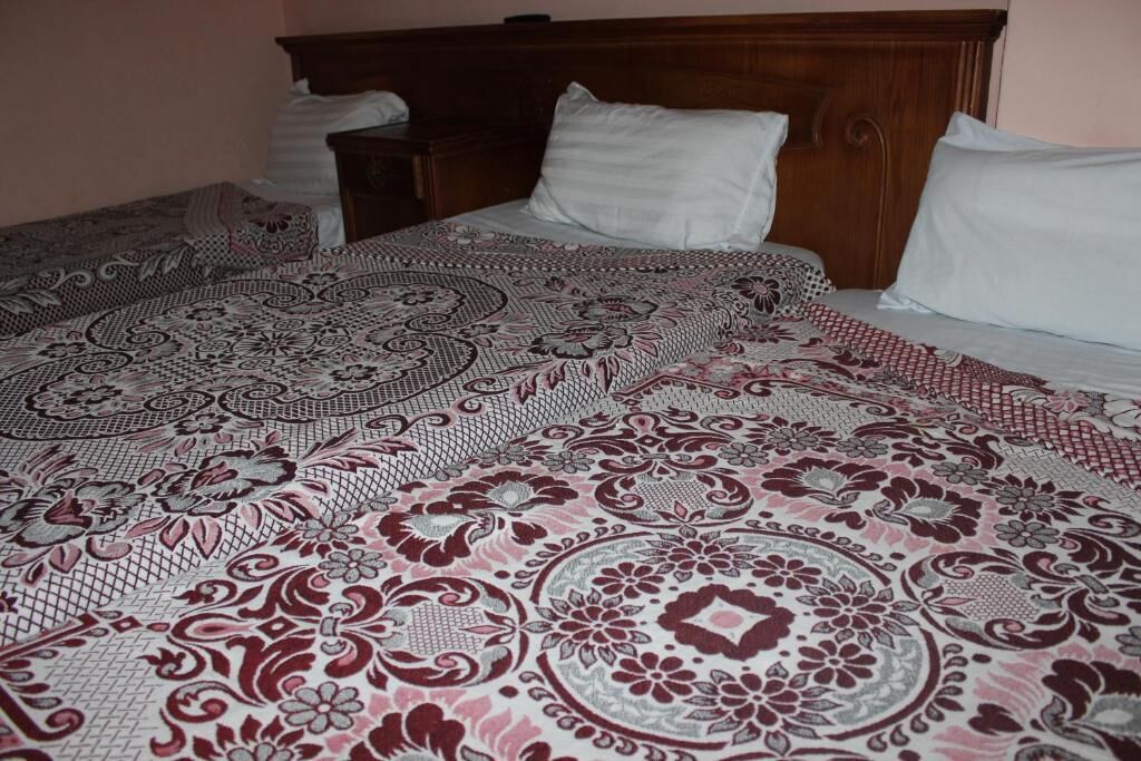A neatly made bed with a patterned bedspread and pillows.