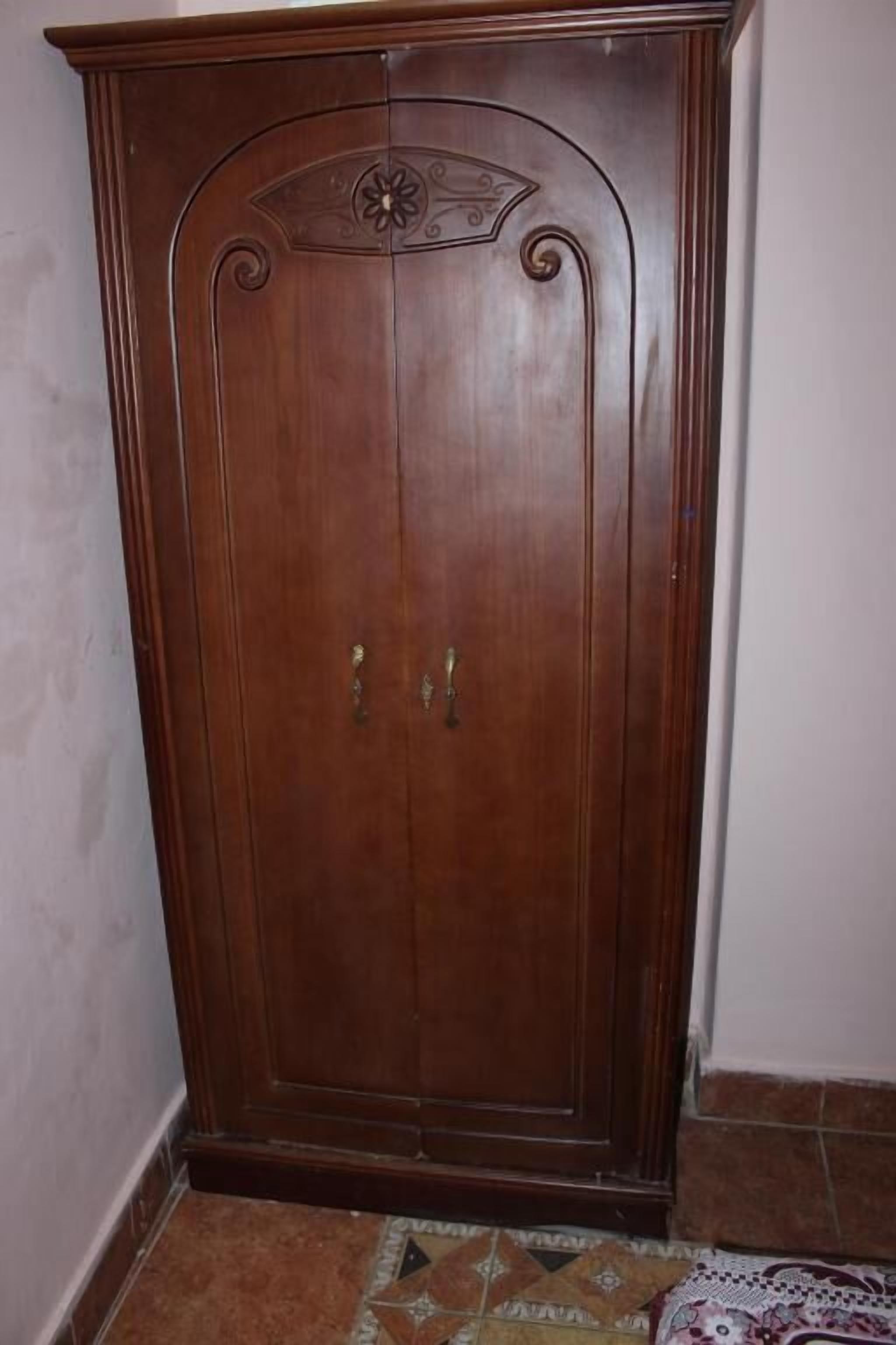Un armario de madera con dos puertas y un adorno en la parte superior.