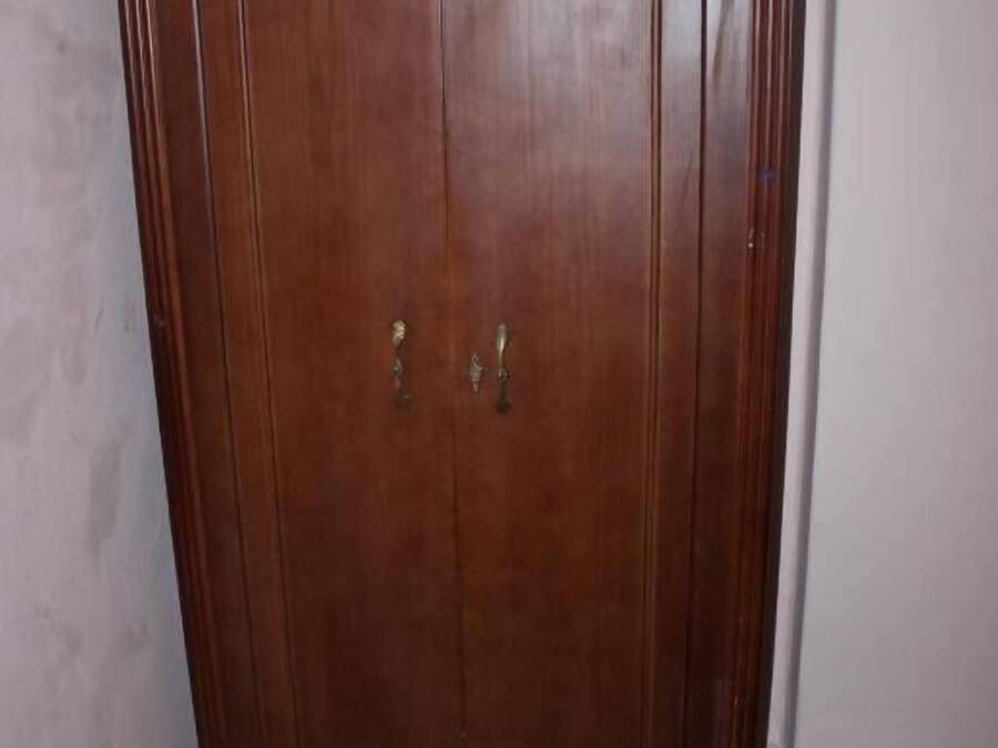 Un armario de madera con dos puertas y un adorno en la parte superior.
