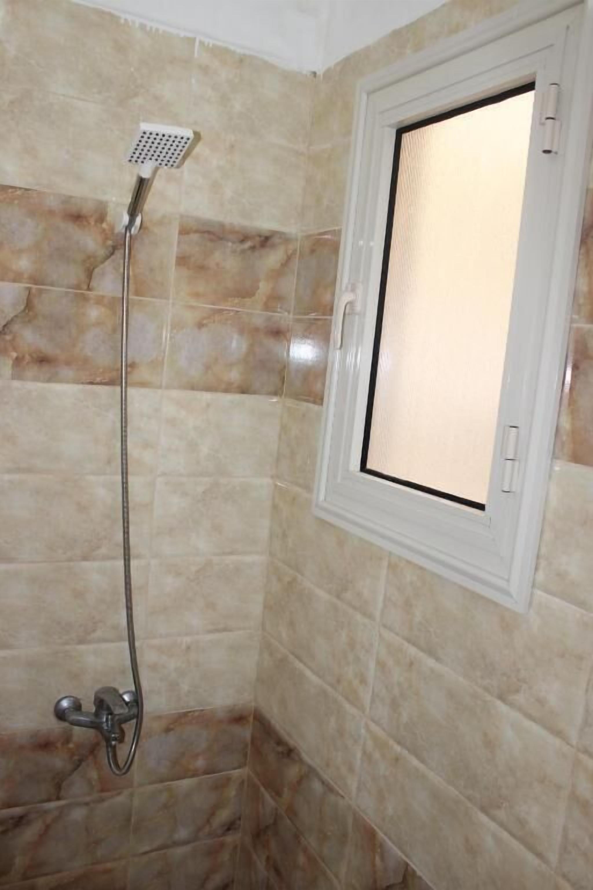 A bathroom with a shower, tiled walls, and a window.