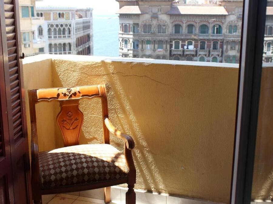 Un balcón con una silla de madera y vistas a edificios históricos.