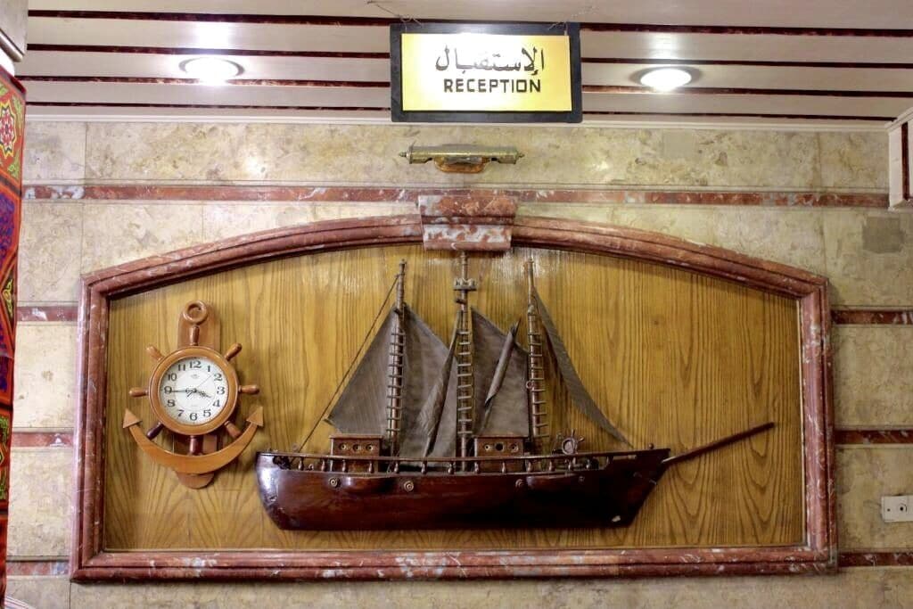 A wooden ship mounted on a wall with a clock below it and a sign above that reads "RECEPTION".